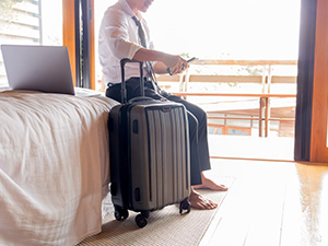 Traveler in Hotel Room on Mobile Device